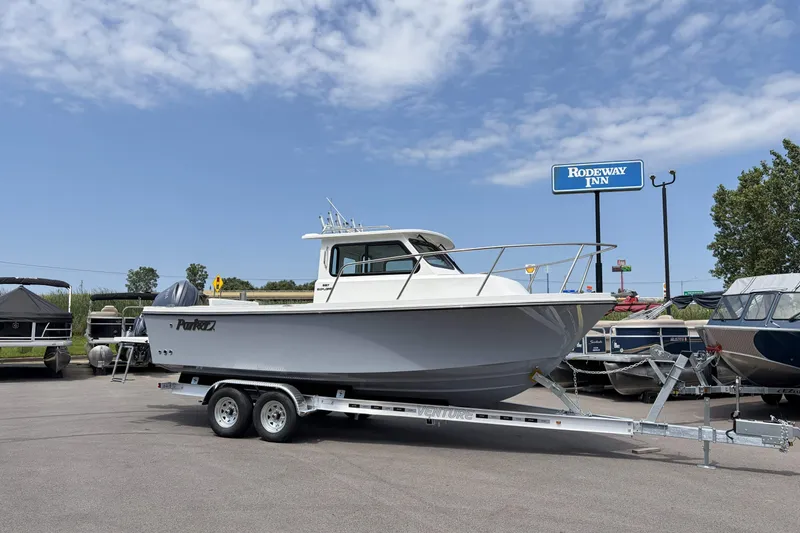 Slide: The Image of 2027 Parker 227 Explorer boat on trailer in parking lot, under clear sky. - 1