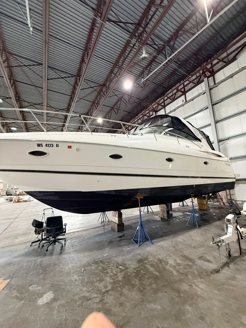 Slide: The Image of A 2004 Cruisers Yachts 400 Express is elevated on stands in a warehouse. - 2