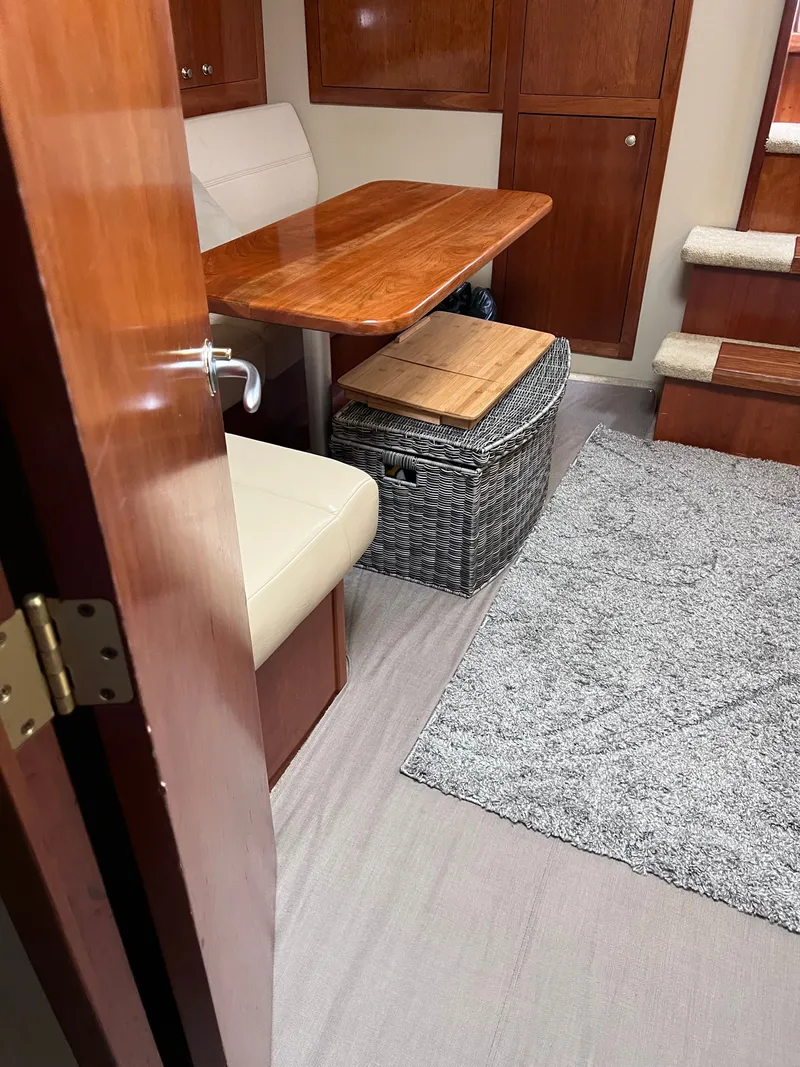 Slide: The Image of Interior of a 2004 Cruisers Yachts 400 Express with a wooden table and bench seating. - 16