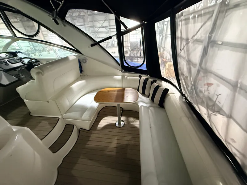 Slide: The Image of Interior of the 2004 Cruisers Yachts 400 Express with white seating area and wooden table. - 7