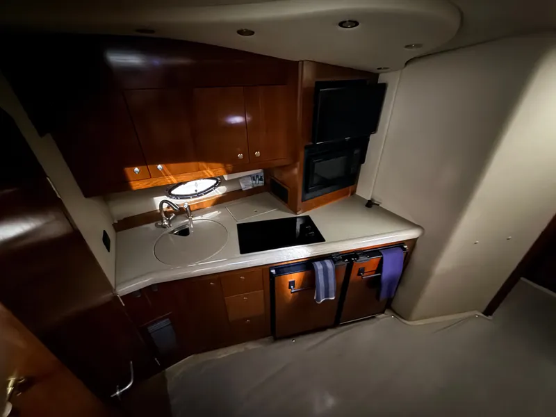 Slide: The Image of The galley of a 2004 Cruisers Yachts 400 Express with wooden cabinets and modern appliances. - 17