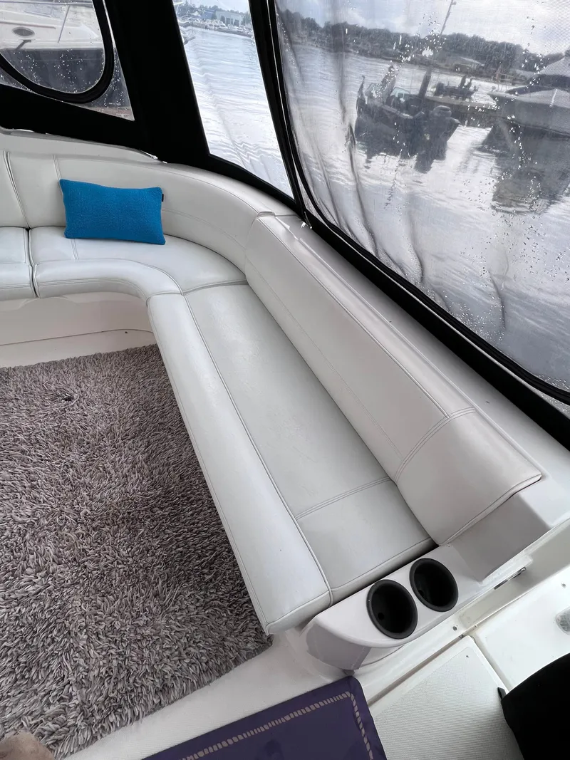 Slide: The Image of Interior of a 2004 Cruisers Yachts 400 Express with white seating and a blue pillow. - 8