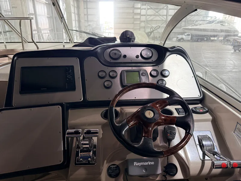 Slide: The Image of The image shows the cockpit of a 2004 Cruisers Yachts 400 Express. It features a wooden steering wheel and modern instruments. - 6