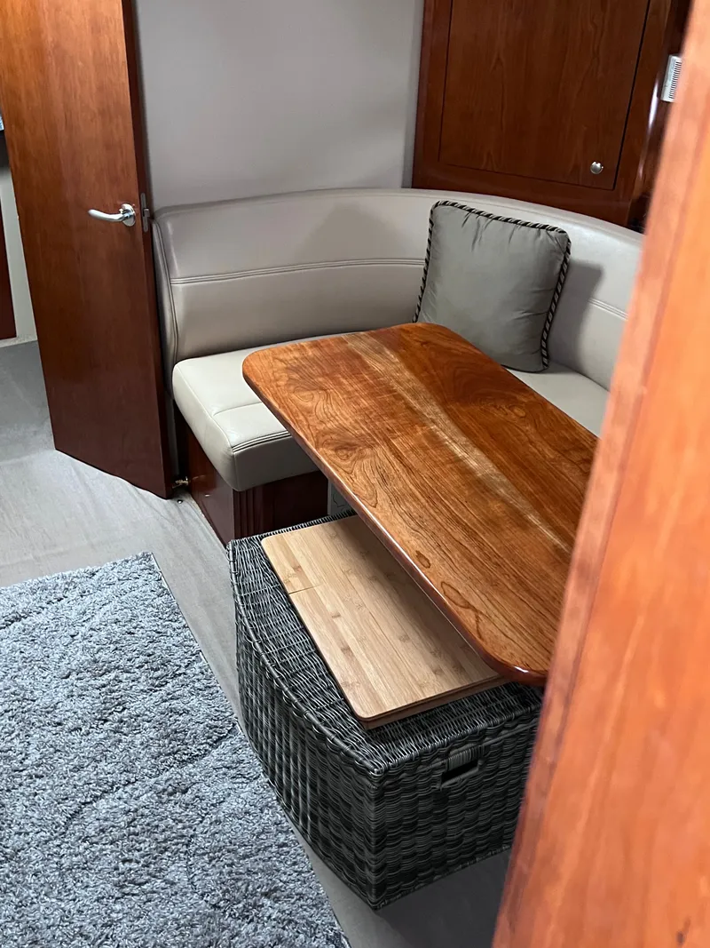 Slide: The Image of Interior of a 2004 Cruisers Yachts 400 Express with a wooden table and beige sofa. - 14