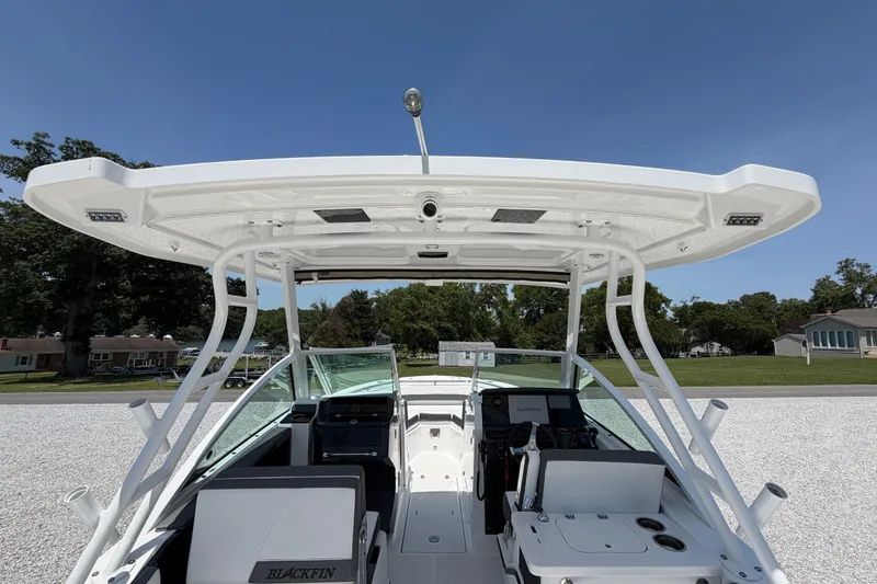 Slide: The Image of 2020 Blackfin 242 DC boat interior with helm, seating, and canopy under clear blue sky. - 25