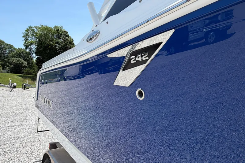 Slide: The Image of 2020 Blackfin 242 DC boat with sleek blue hull, parked on gravel. - 10