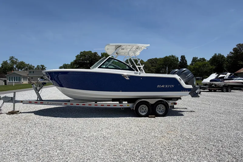 Slide: The Image of 2020 Blackfin 242 DC boat on trailer, parked outdoors under clear blue sky. - 7