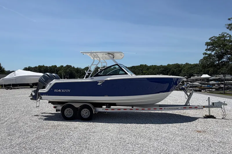 Slide: The Image of 2020 Blackfin 242 DC boat on trailer, parked outdoors under clear sky. - 14