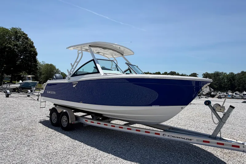 Slide: The Image of 2020 Blackfin 242 DC boat on trailer, parked outdoors under clear blue sky. - 12