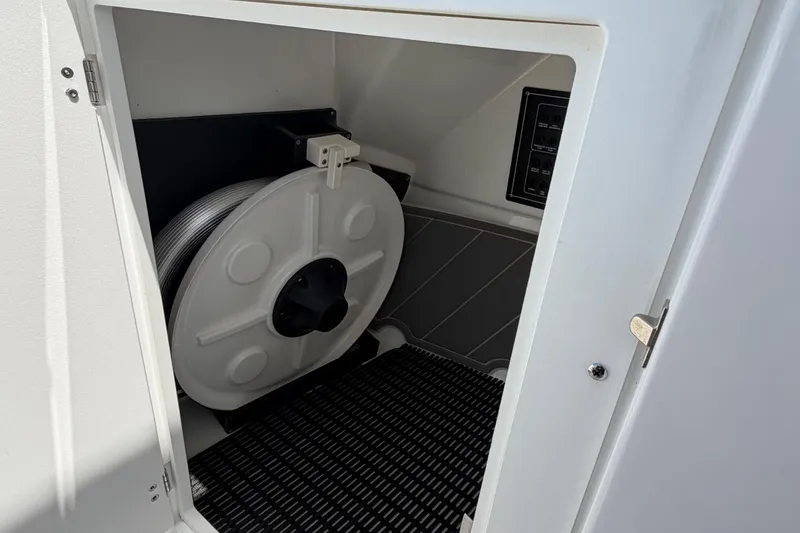 Slide: The Image of Storage compartment in a 2020 Blackfin 242 DC boat, featuring a coiled hose reel. - 29