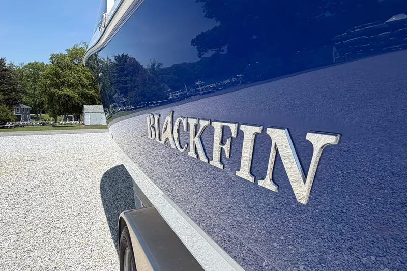 Slide: The Image of 2020 Blackfin 242 DC boat with reflective blue hull and logo in a sunny outdoor setting. - 8