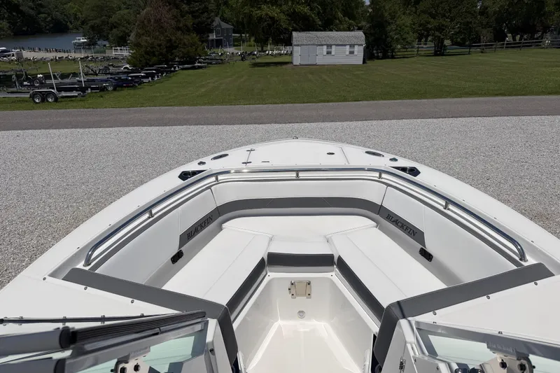 Slide: The Image of 2020 Blackfin 242 DC boat interior with seating, parked near a grassy area. - 44