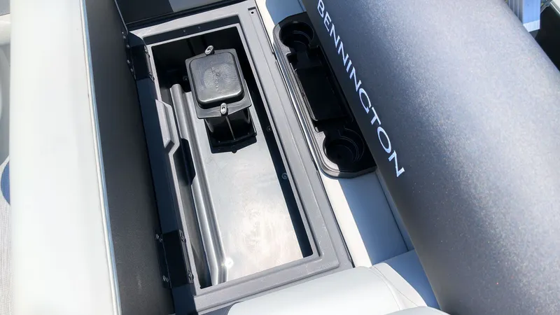 Slide: The Image of A storage compartment on a Bennington boat with a black lid and cup holders. - 9