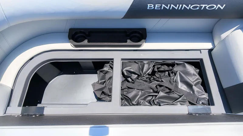 Slide: The Image of A storage compartment on a Bennington boat with black covers and cup holders. - 16