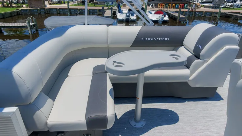 Slide: The Image of The image shows the seating area of a Bennington 18 S CRUISE pontoon boat. It features gray upholstery and a table with cup holders. - 7