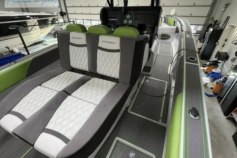Slide: The Image of 2017 Statement 380 Open boat interior with green and gray seating in a garage setting. - 27