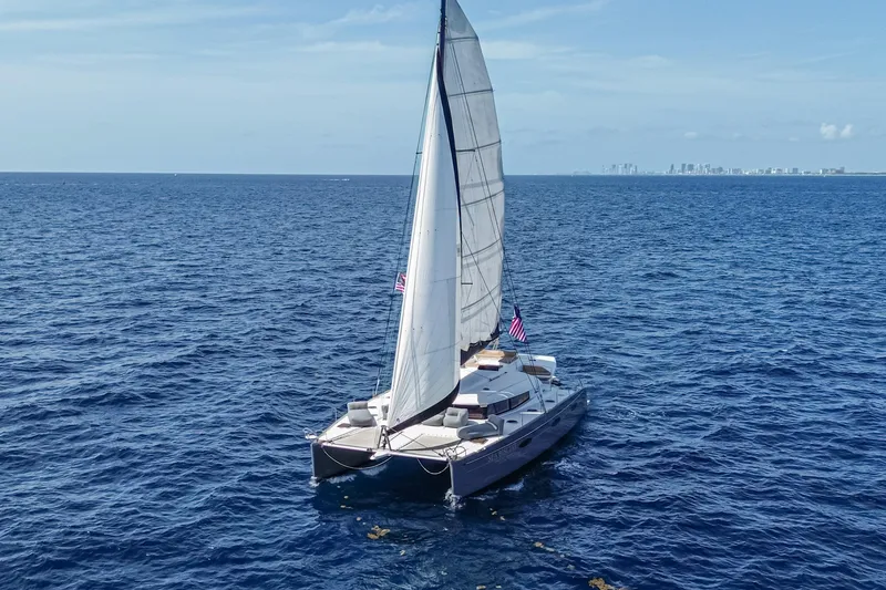 The Image of 2015 Fountaine Pajot Sanya 57 sailing on open ocean with city skyline in background. - 0