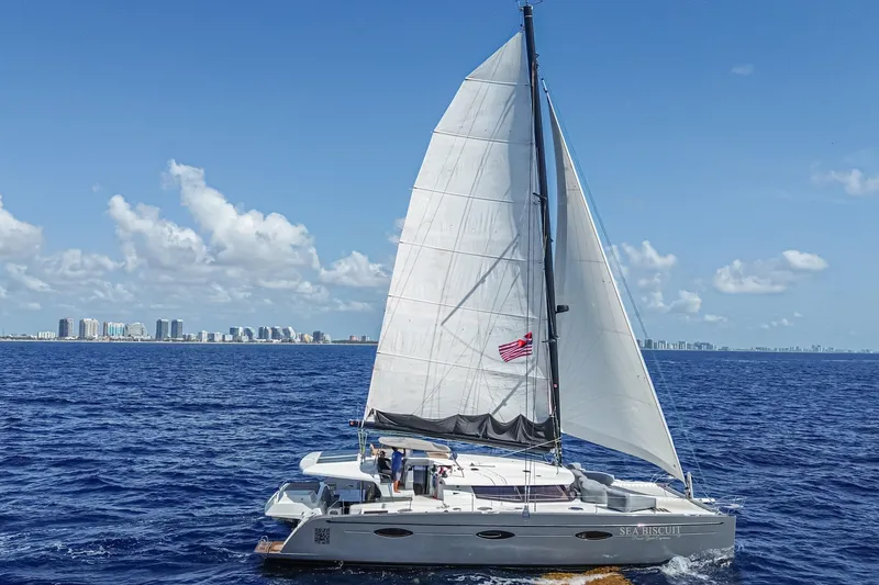 Slide: The Image of 2015 Fountaine Pajot Sanya 57 sailing on open sea with city skyline in background. - 47