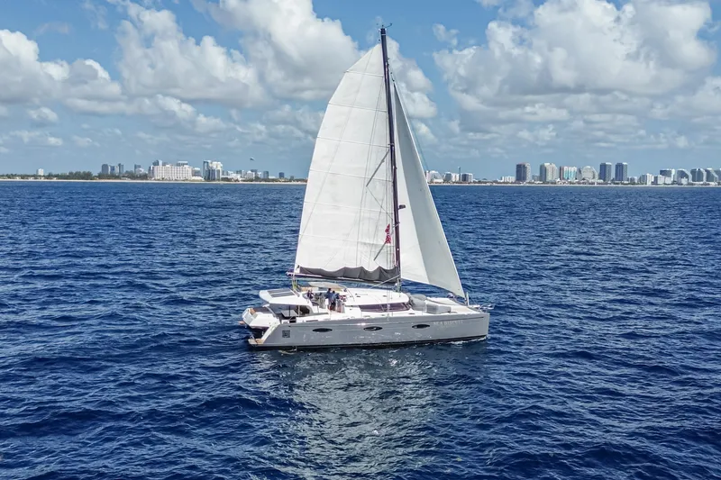 Slide: The Image of Sailing catamaran Fountaine Pajot Sanya 57, 2015 model, cruising near a coastal city skyline. - 56