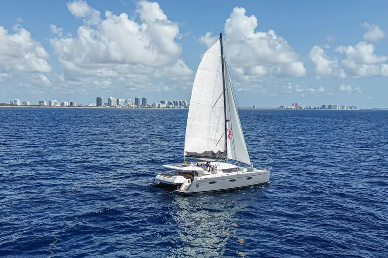 Slide: The Image of Sailing catamaran Fountaine Pajot Sanya 57, 2015, cruising on open sea with city skyline backdrop. - 64