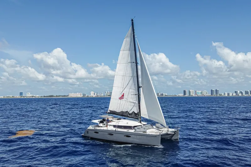 Slide: The Image of 2015 Fountaine Pajot Sanya 57 sailing on open sea with city skyline in background. - 61