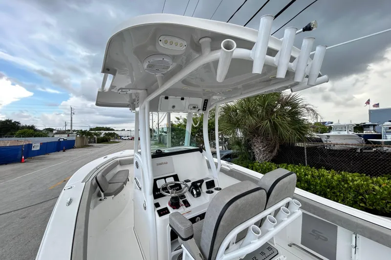 Slide: The Image of 2023 Sea Pro 259 Center Console boat with modern helm and rod holders, docked under cloudy skies. - 22