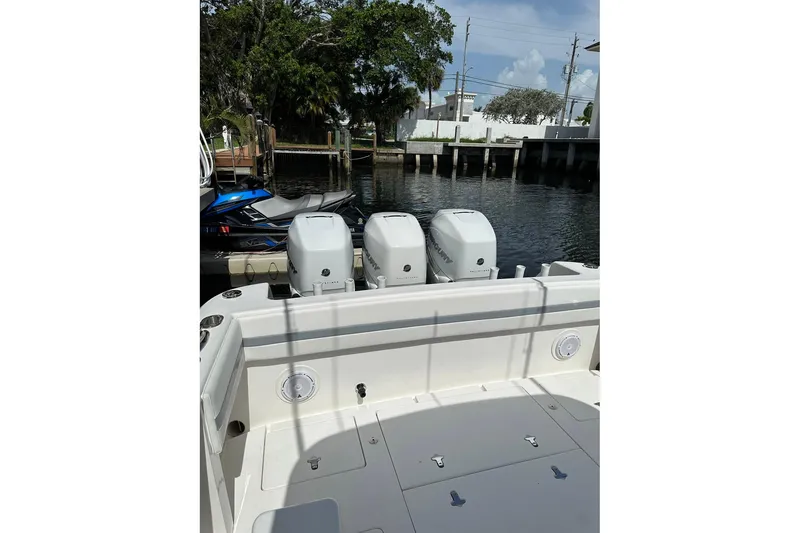 Slide: The Image of 2013 Intrepid 375 Center Console boat with triple outboard engines docked by the water. - 29