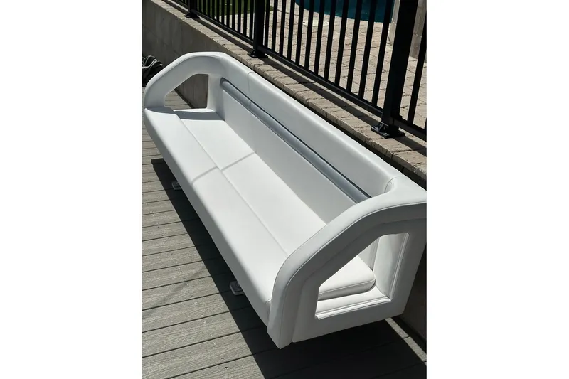 Slide: The Image of White bench seat from a 2013 Intrepid 375 Center Console boat, on a wooden deck. - 22