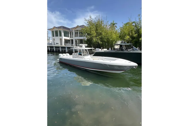 Slide: The Image of 2013 Intrepid 375 Center Console boat docked near a modern waterfront home. - 1