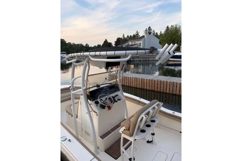 Slide: The Image of 2018 Scout 215 XSF boat with helm and seating, docked by a serene waterfront. - 5