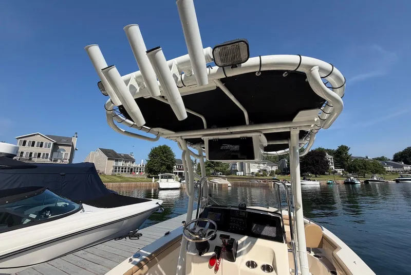 Slide: The Image of 2018 Scout 215 XSF boat docked, featuring a T-top and rod holders. - 25