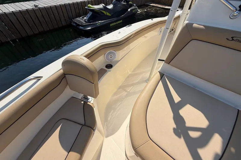 Slide: The Image of 2018 Scout 215 XSF boat interior with beige seating and nearby jet ski. - 20