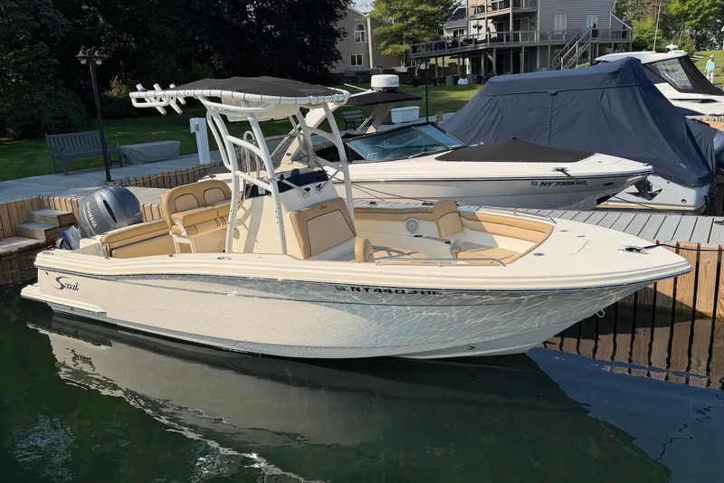 Slide: The Image of 2018 Scout 215 XSF boat docked at marina, featuring sleek design and beige interior. - 7