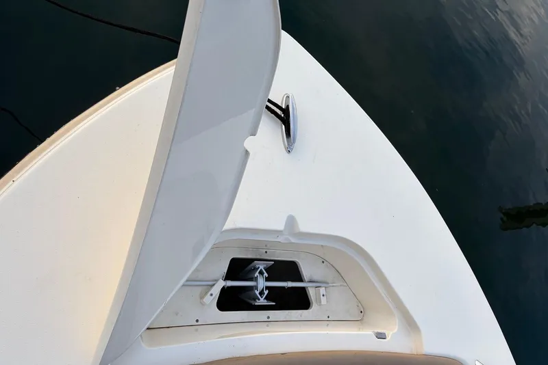 Slide: The Image of 2018 Scout 215 XSF boat anchor compartment, open hatch, docked on calm water. - 3