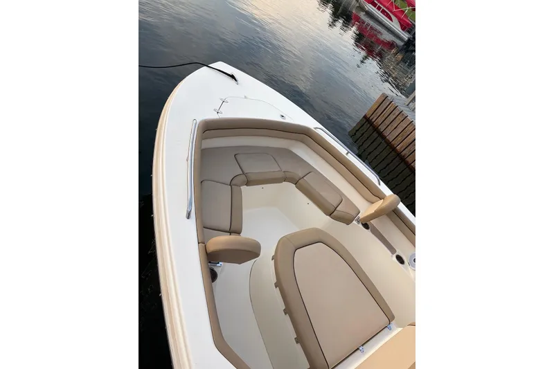 Slide: The Image of 2018 Scout 215 XSF boat interior with beige seating, docked by calm water. - 2