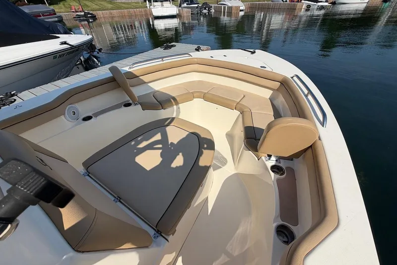 Slide: The Image of 2018 Scout 215 XSF boat interior with beige seating, docked by the water. - 16
