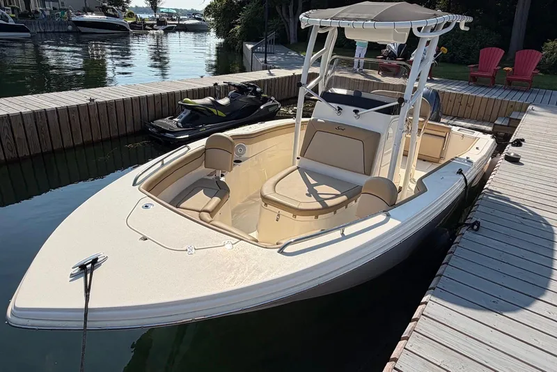 Slide: The Image of 2018 Scout 215 XSF boat docked by a wooden pier, with a jet ski nearby. - 6