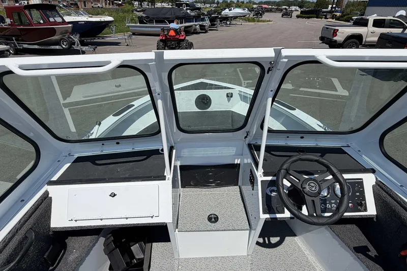 Slide: The Image of 2027 Crestliner 1850 Commander boat interior with steering wheel and dashboard, parked in a marina. - 9