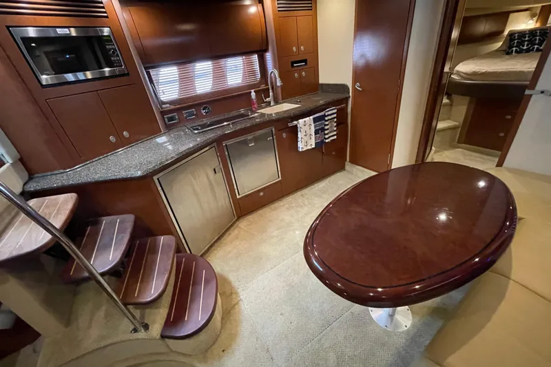 Slide: The Image of 2007 Sea Ray 40 Sundancer interior with kitchen, dining table, and cozy sleeping area. - 26