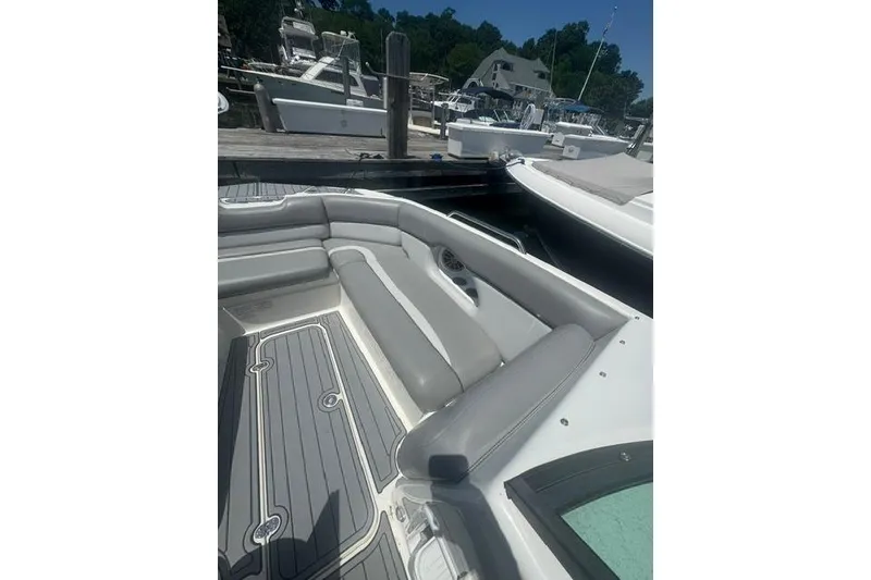 Slide: The Image of 2021 NauticStar 243 DC boat interior with gray seating at a marina. - 6