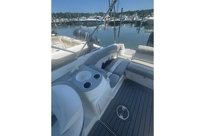 Slide: The Image of 2021 NauticStar 243 DC boat interior with seating and cup holders at marina. - 14