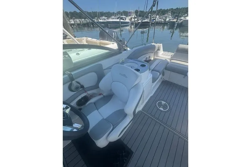 Slide: The Image of 2021 NauticStar 243 DC boat interior with helm seat and marina view. - 12