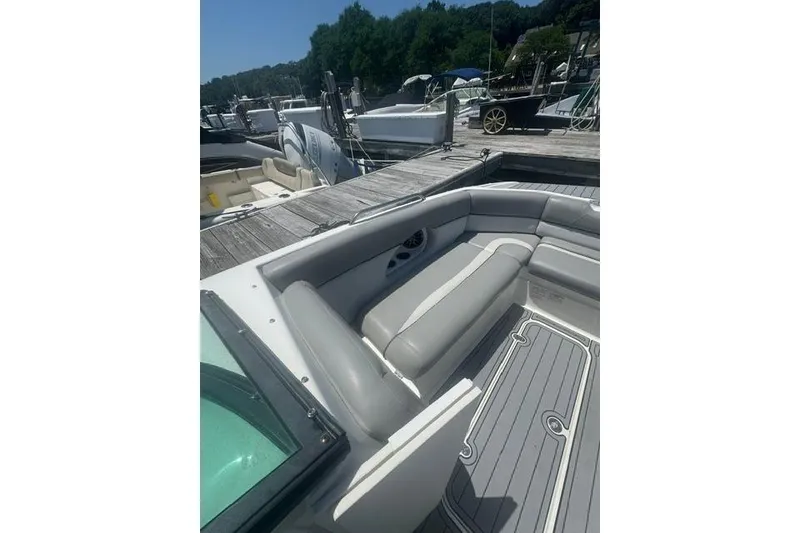 Slide: The Image of 2021 NauticStar 243 DC boat interior with gray seating at a marina dock. - 5