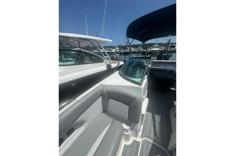 Slide: The Image of 2021 NauticStar 243 DC boat interior with seating and canopy in a marina setting. - 7