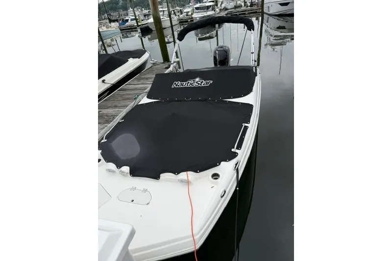 Slide: The Image of 2021 NauticStar 243 DC boat docked with black cover in marina. - 22