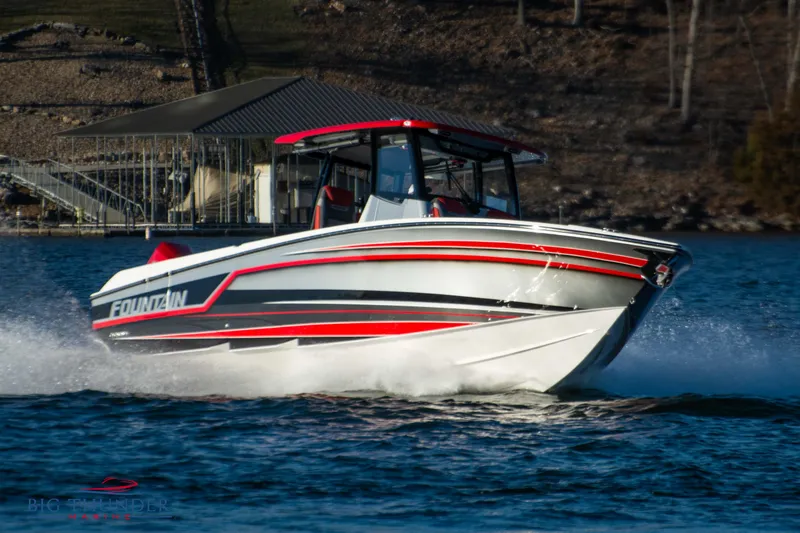 Slide: The Image of A 2023 Fountain 32 NX boat speeds across the water, featuring red and black accents. - 1