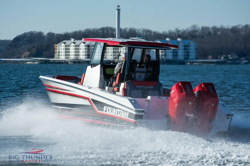 Slide: The Image of 2023 Fountain 32 NX on the water with twin outboard engines, buildings in the background. - 12