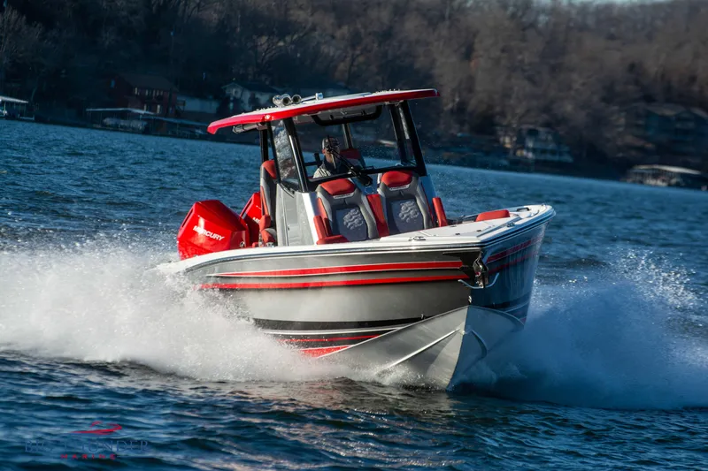 Slide: The Image of A 2023 Fountain 32 NX boat speeds across the water, featuring red accents and twin outboard engines. - 2