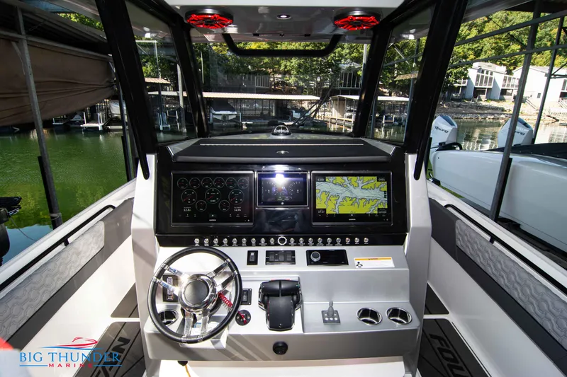 Slide: The Image of The 2023 Fountain 32 NX cockpit features a modern helm with dual screens. - 30