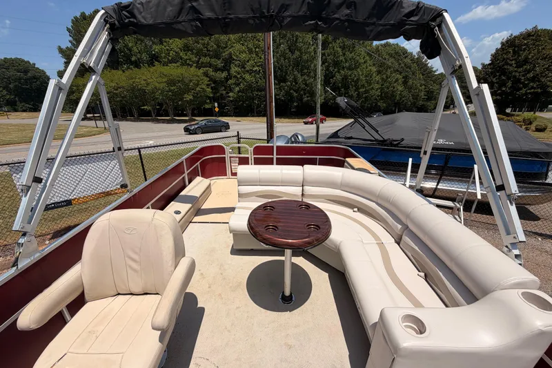 Slide: The Image of 2013 Veranda 24 pontoon boat with spacious seating and table, parked outdoors. - 7